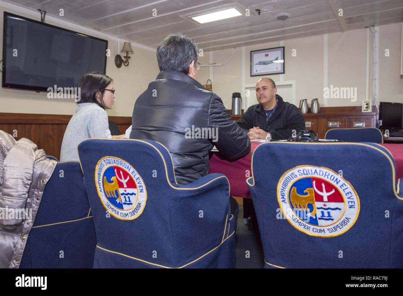 SASEBO, Japan (Jan. 18, 2017) Kapitän George Doyon (rechts), Commander, Amphibischen Squadron (PHIBRON) 11, nimmt in einem Interview mit sunao Gushiken (Mitte), Journalist der japanischen Zeitung Asahi Shimbun, an Bord amphibisches Schiff USS BONHOMME RICHARD (LHD6). Bonhomme Richard, Vorwärts- und Sasebo, Japan bereitgestellt, das eine schnelle Reaktionsfähigkeit im Falle eines regionalen Kontingenz oder Naturkatastrophe zur Verfügung zu stellen. Stockfoto