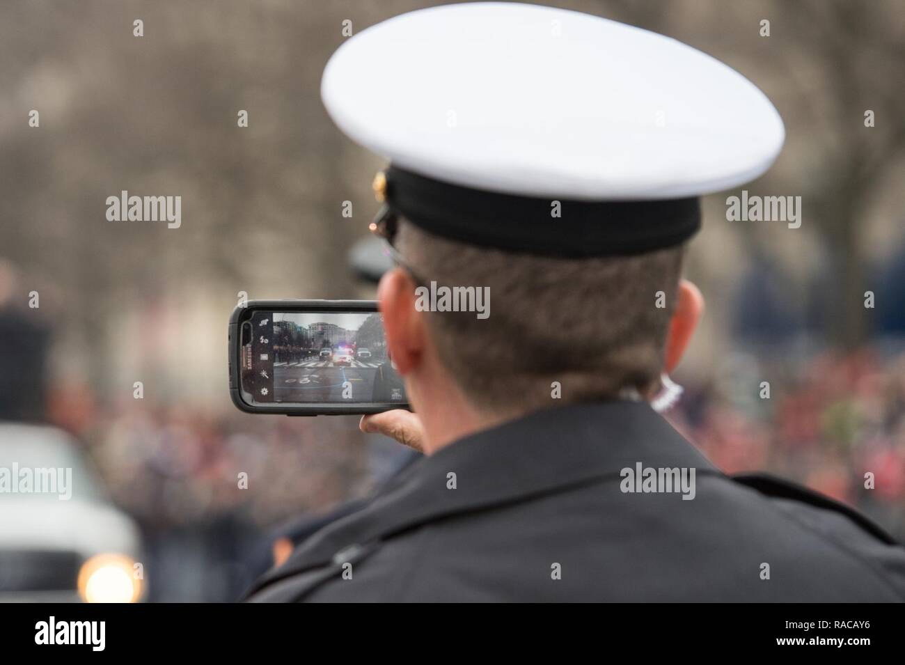 Ein Service die Uhren der Eröffnungs-Parade während der Aufnahme der Präsidiale Autokolonne auf seiner Kamera Handy in Washington, D.C., 20 Jan, 2017. Mehr als 50.000 militärische Mitglieder aus über alle Niederlassungen der Streitkräfte der Vereinigten Staaten, einschließlich der Reserven und National Guard Komponenten, sofern zeremoniellen Unterstützung und Verteidigung Unterstützung der zivilen Behörden bei der Eröffnungs-Periode. Stockfoto