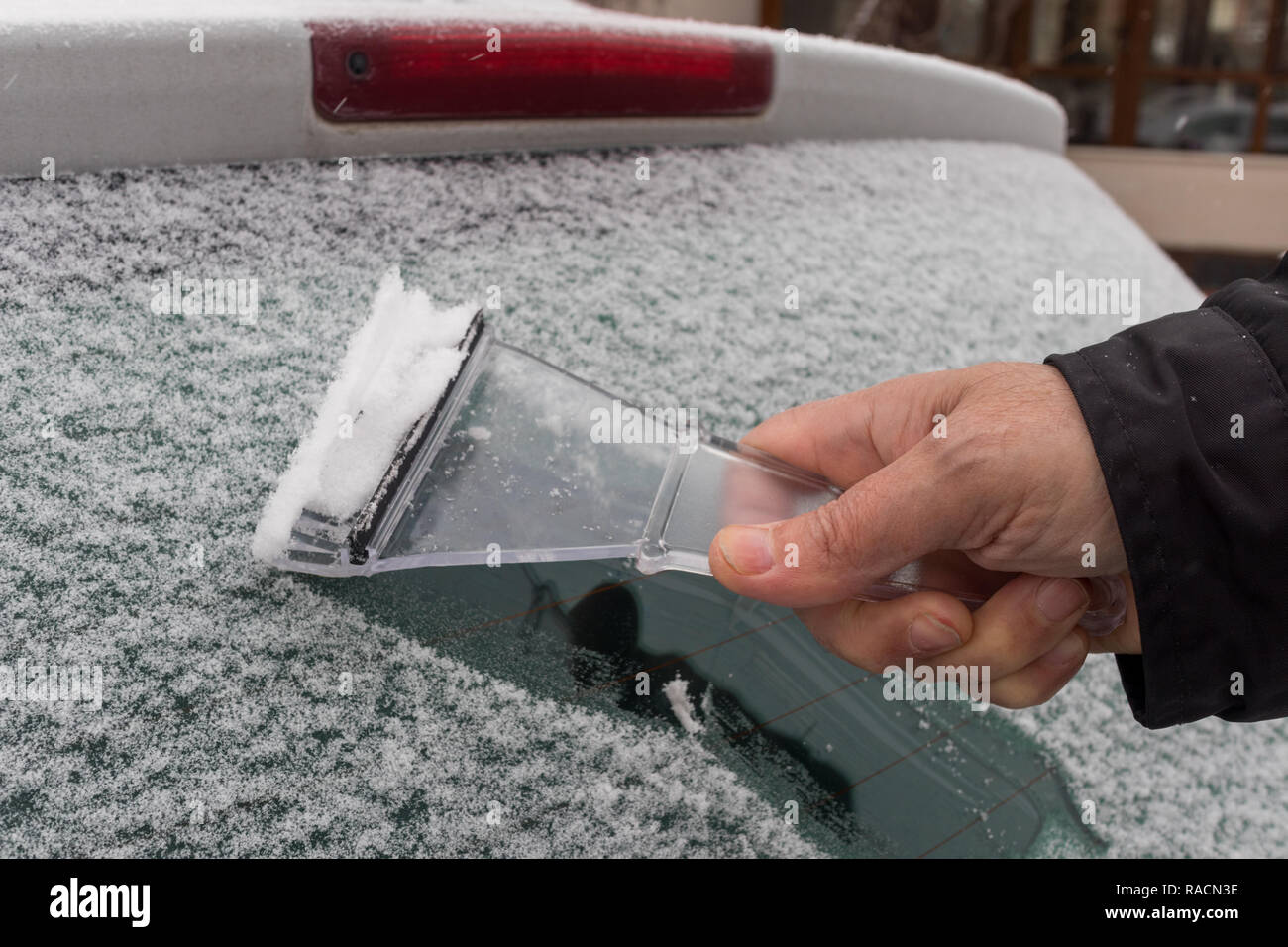 Mann Reinigung der Schnee auf seinem Auto Fenster Stockfoto