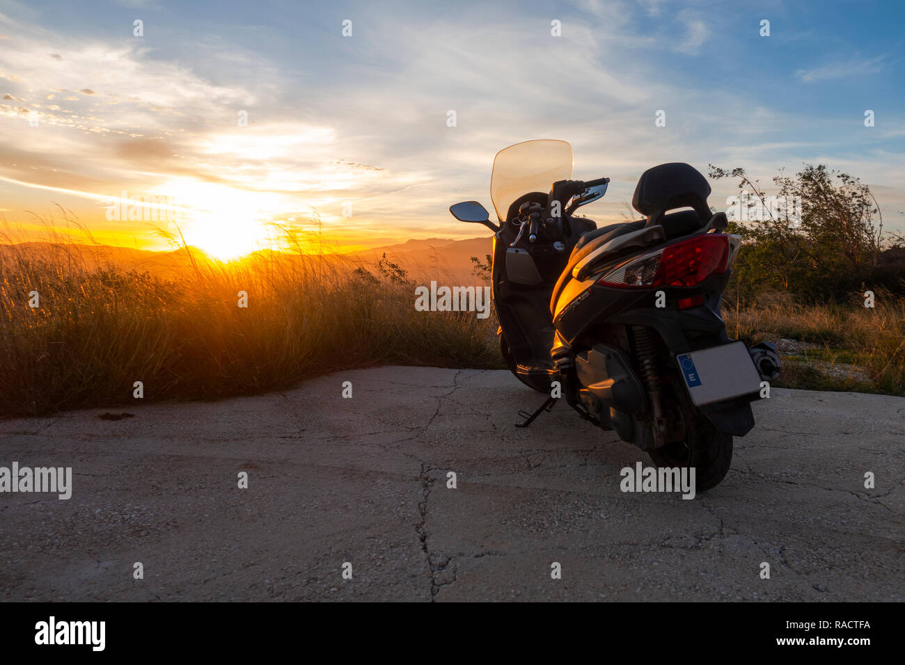 Motorrad, Roller bei Sonnenuntergang auf ending Road, Spanien geparkt. Stockfoto