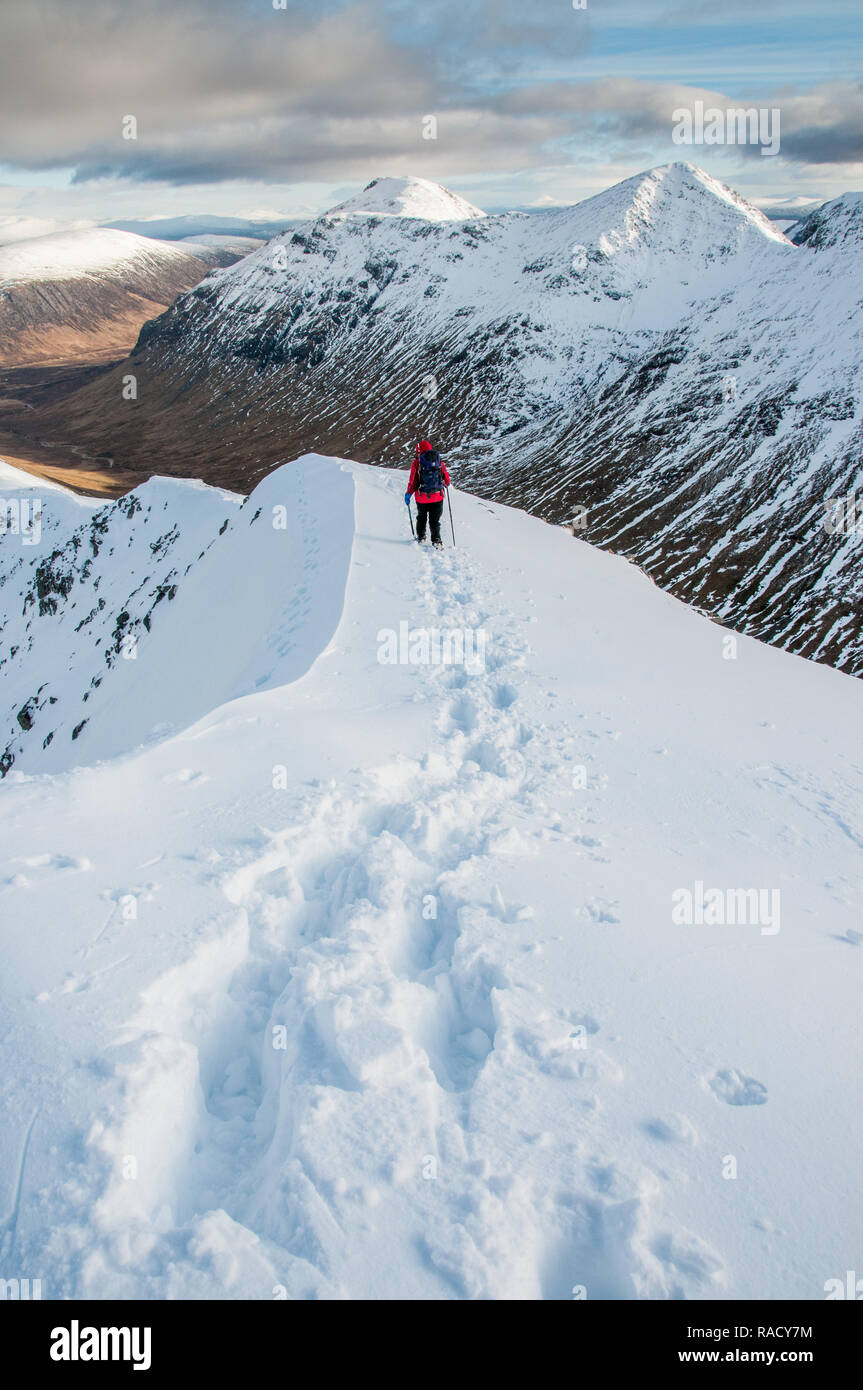 Eine weibliche Walker Abstieg vom Gipfel des Stob Dubh auf Buchaille Etive Beag an einem klaren Wintertag, Highlands, Schottland, Großbritannien, Europa Stockfoto