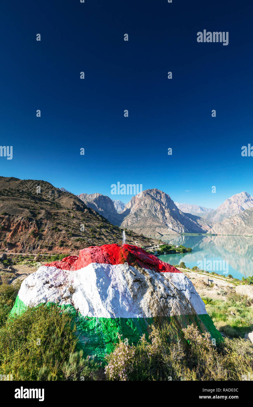 Iskanderkul See mit einem großen Felsen in den Farben der Flagge Tadschikistan im Vordergrund gemalt, Fan Gebirge, Tadschikistan, Zentralasien, Asien Stockfoto