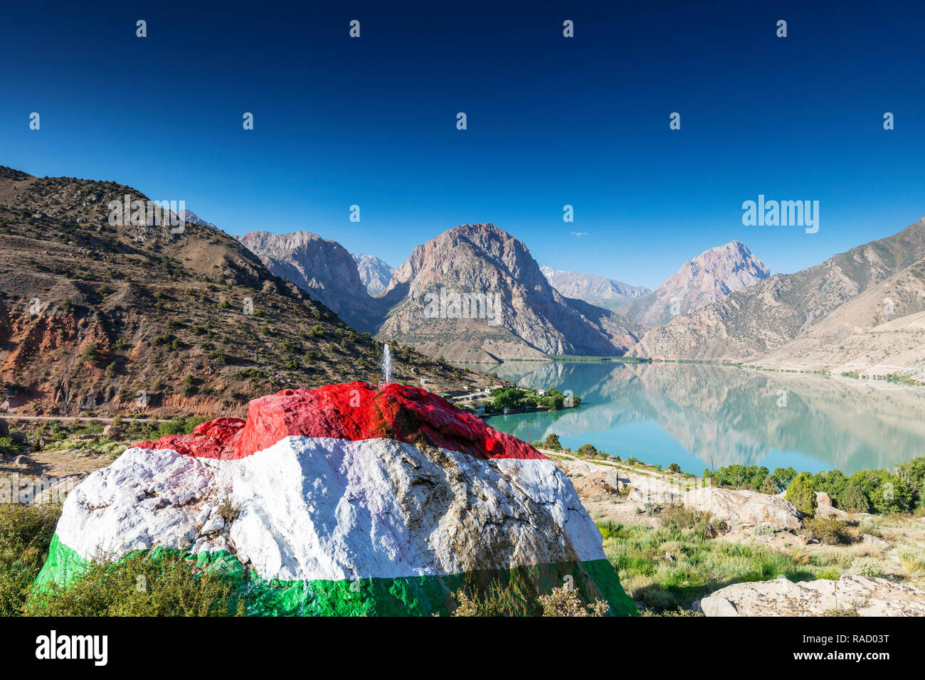 Iskanderkul See mit einem großen Felsen in den Farben der Flagge Tadschikistan im Vordergrund gemalt, Fan Gebirge, Tadschikistan, Zentralasien, Asien Stockfoto