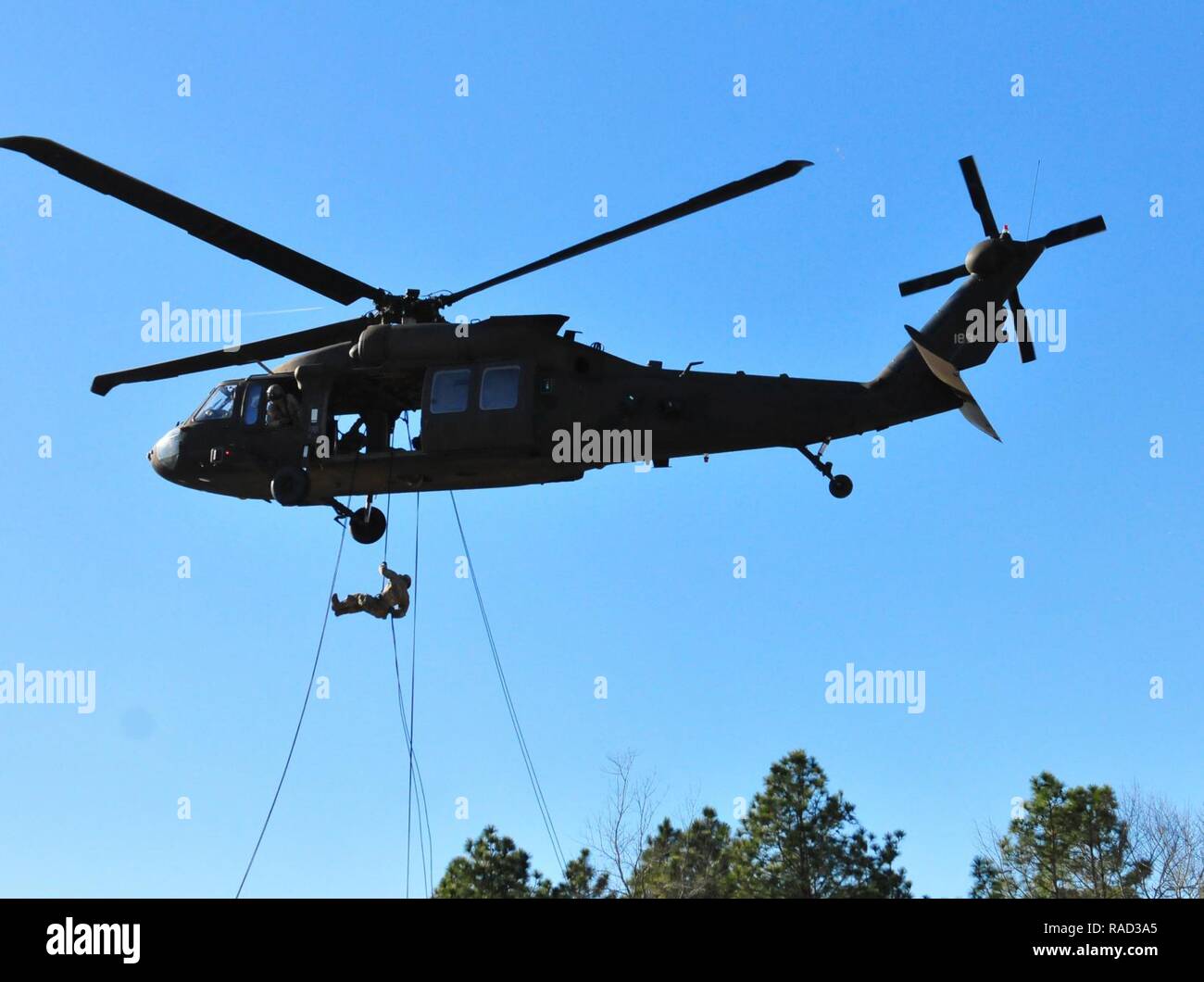 Die Kursteilnehmer auf das XVIII Airborne Corps' DeGlopper Air Assault School, Fort Bragg, N.C. zugewiesen sind, nehmen an den Air Assault Ausbildung Jan. 25, 2017. Die Ausbildung ist der Mähdrescher mit rappel Techniken von einem UH-60 Black Hawk, wie es schwebt 100 Fuß auf Simmons Flugplatz. Stockfoto