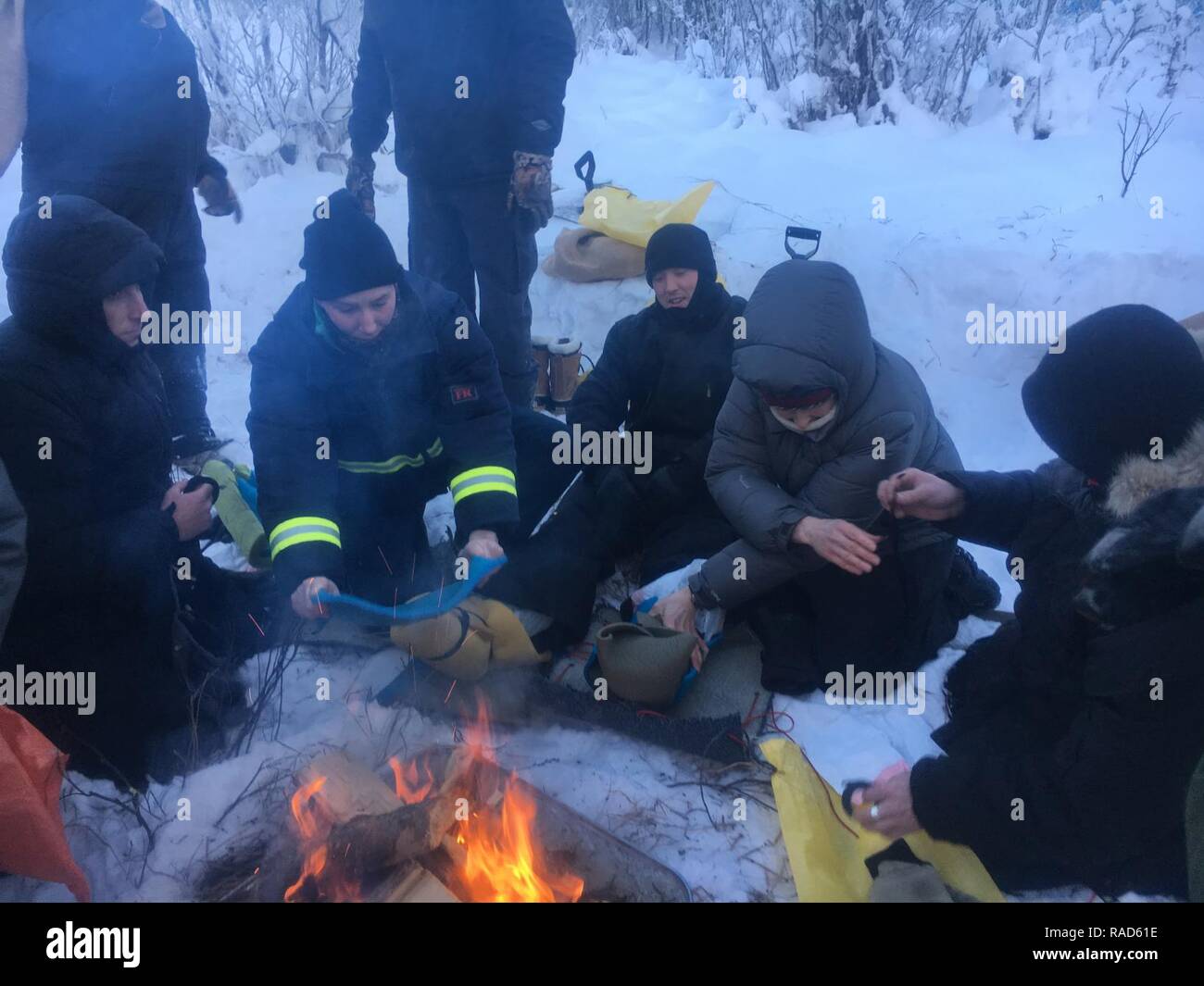 Mitglieder der Küstenwache Sektor Anchorage Stiefel machen aus dem Flugzeug  Sitzkissen rund um ein Feuer, die Sie als Teil des kalten Wetters  Überlebenstraining in den Wäldern von Anchorage, Alaska, Jan. 19, 2017.