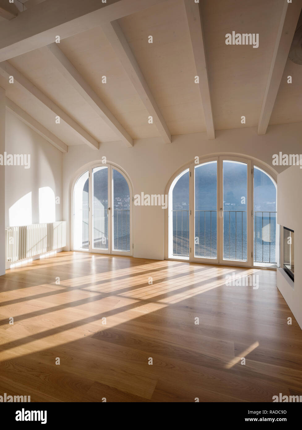 Leere Zimmer mit einem großen Fenster mit Blick auf den See. Antike Holzbalken an der Decke einer renovierte Wohnung Stockfoto