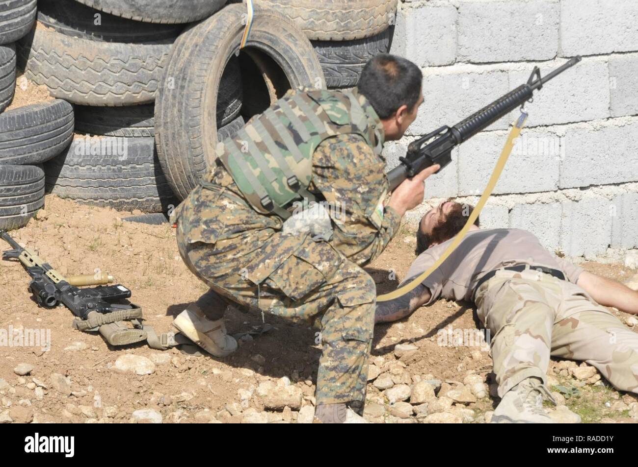 Ein peshmerga Soldat vorsichtig nähert sich einem "Feind", ein Niederländischer Soldat gespielt, während urban Operations Training in der Nähe von Erbil, Irak. Niederländische und norwegische Soldaten, Teil der Kurdistan Training Coordination Center, beaufsichtigte Ausbildung ist der Tag, den der einzelnen Bewegung Techniken enthalten, Counter IED und Einlasskontrolle verfahren. Die KTCC ist eine multi-nationale Koalition für die Ausbildung, Beratung und Unterstützung der kurdischen Truppen ISIL im Irak zu besiegen. Stockfoto