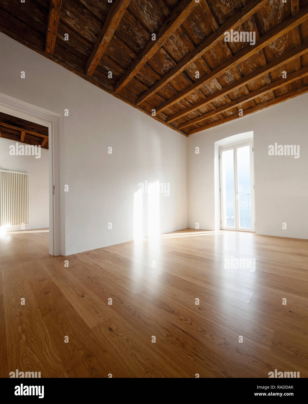 Leere Zimmer mit einem großen Fenster mit Blick auf den See. Antike Holzbalken an der Decke einer renovierte Wohnung Stockfoto