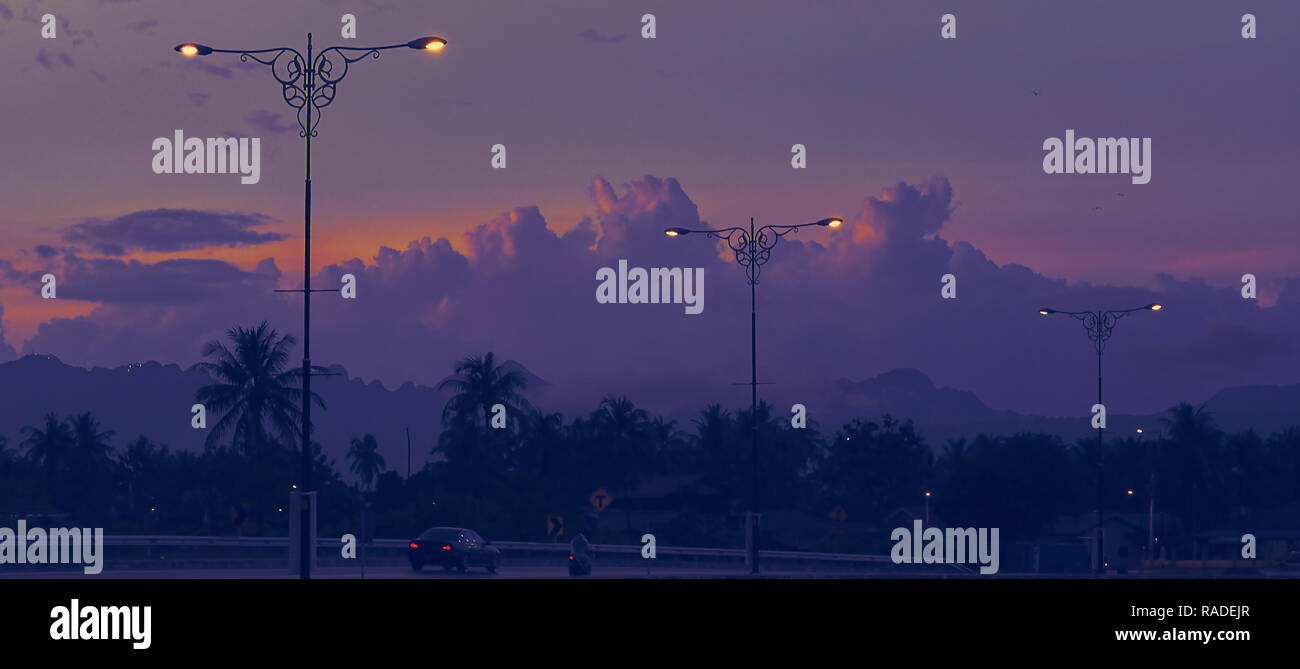 Asiatische Sonnenuntergang an der Straße mit Lampen Straße in silhouette Ton. Urban Street, Auto und Strassenlaternen im Hintergrund. Stockfoto