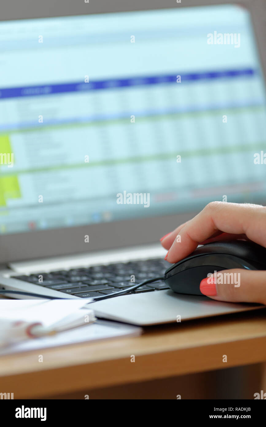 Hintergründe und Texturen: weibliche Hand, die eine Computermaus, mit Laptop, Tabellen auf dem Bildschirm Stockfoto