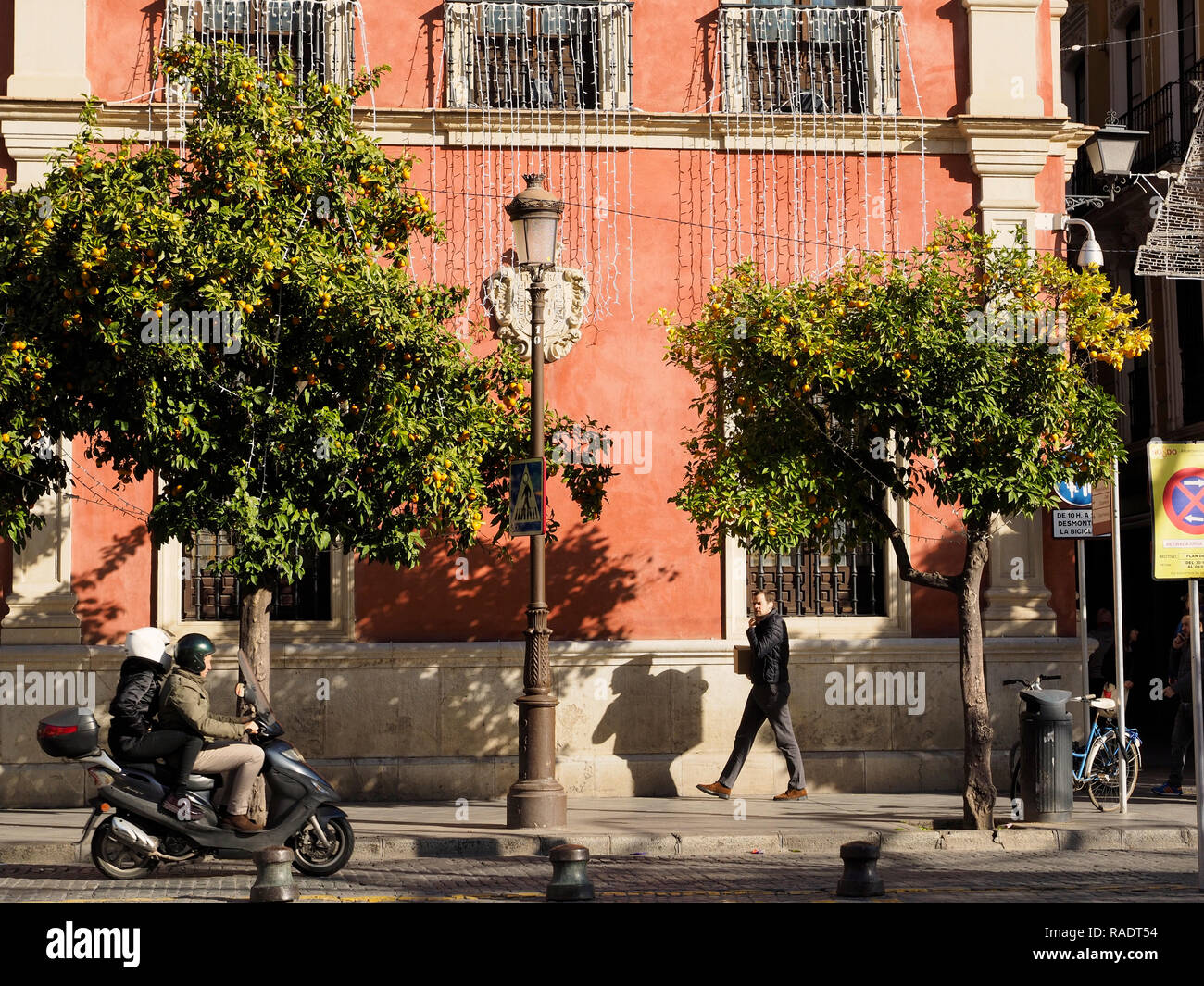 Sevilla, Andalusien, Spanien, street scene mit bunten Gebäude, typisch orange Bäume voller Früchte, und die Leute reiten ein scooter. Stockfoto