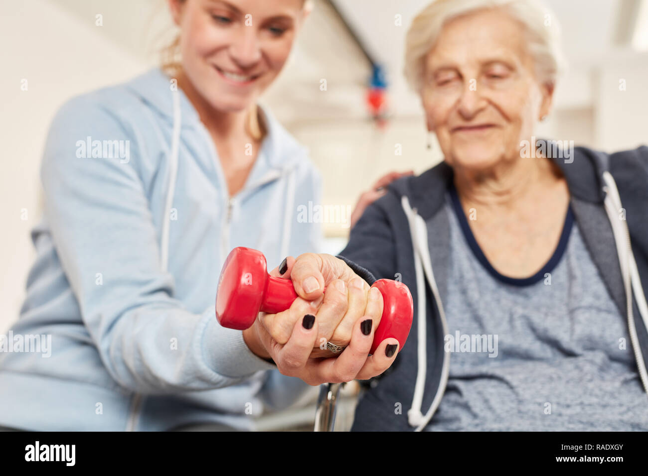 Physiotherapeut hilft, ältere Frau mit gesunden Hantel Training im rehab Stockfoto