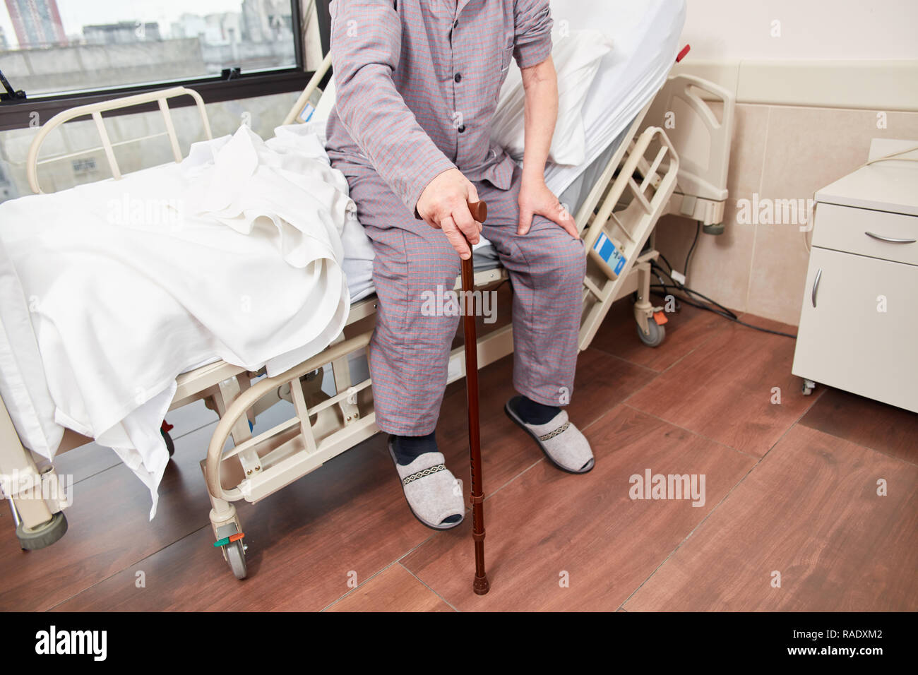 Patienten mit krücke sitzt auf seinem Bett in der Reha Klinik oder im Krankenhaus Stockfoto