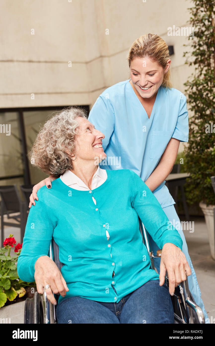 Senior im Rollstuhl und Betreuer in der Reha Klinik oder Pflegeheim Stockfoto