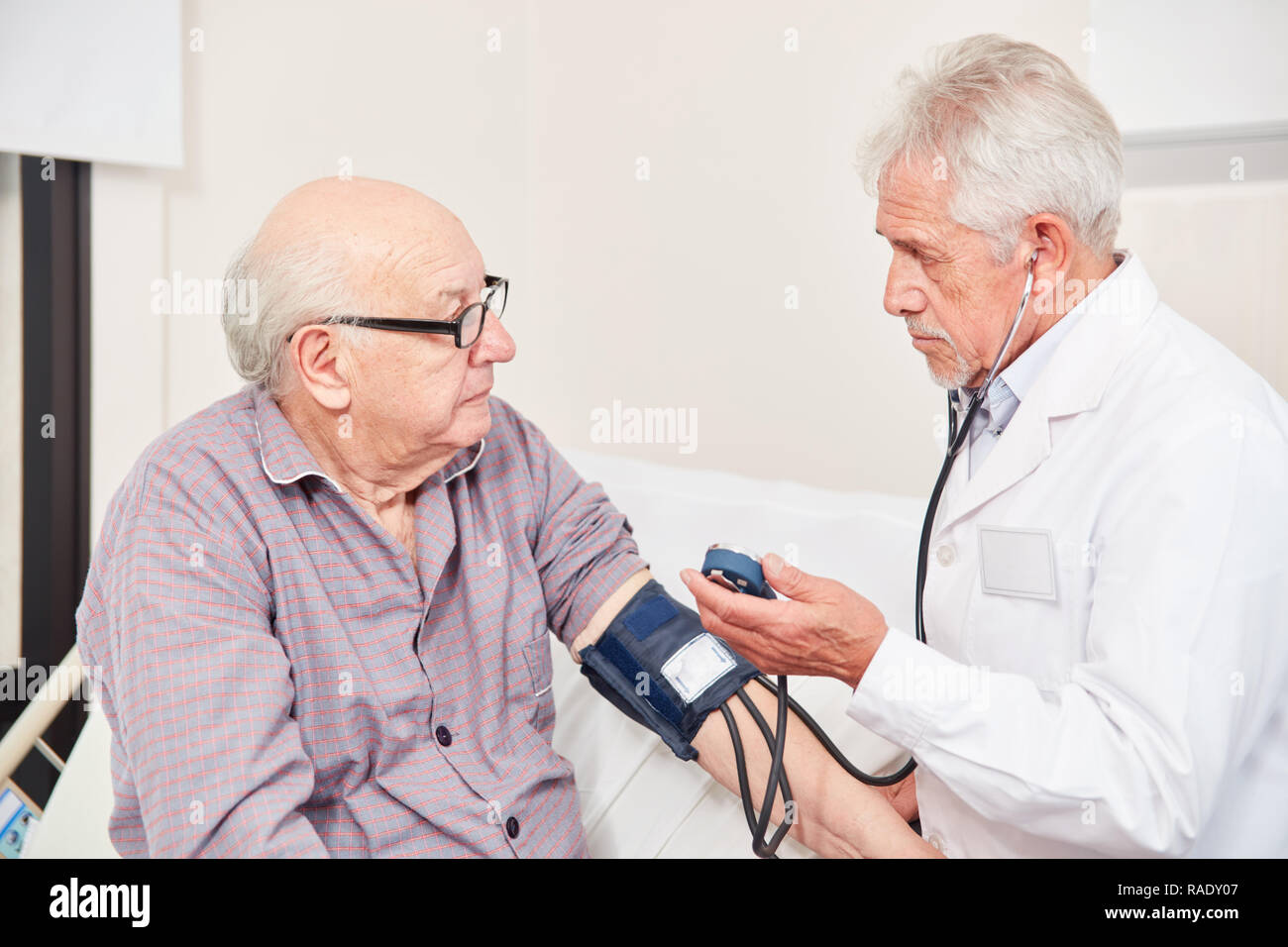Arzt Blutdruck messen in einem alten Mann, der als Kontrolle in Bluthochdruck Stockfoto