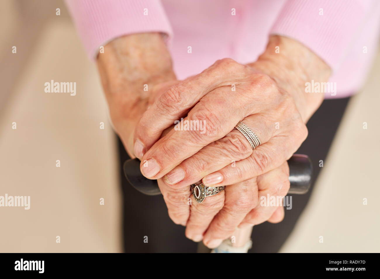 Faltigen Hände einer alten Frau Lean auf eine Krücke stick Stockfoto