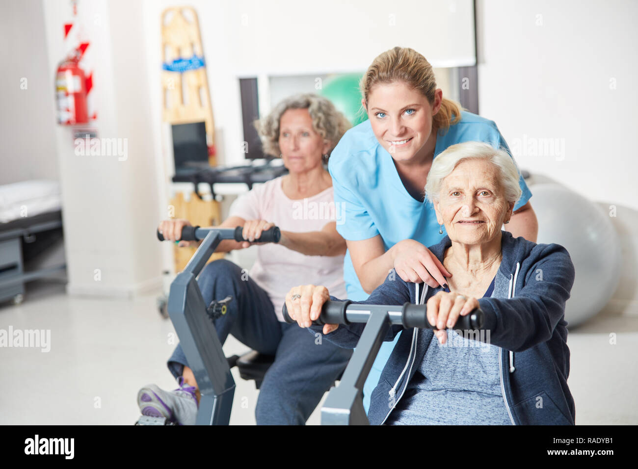 Trainer hilft Senioren mit Ergometer Training für Ausdauer im rehab Stockfoto