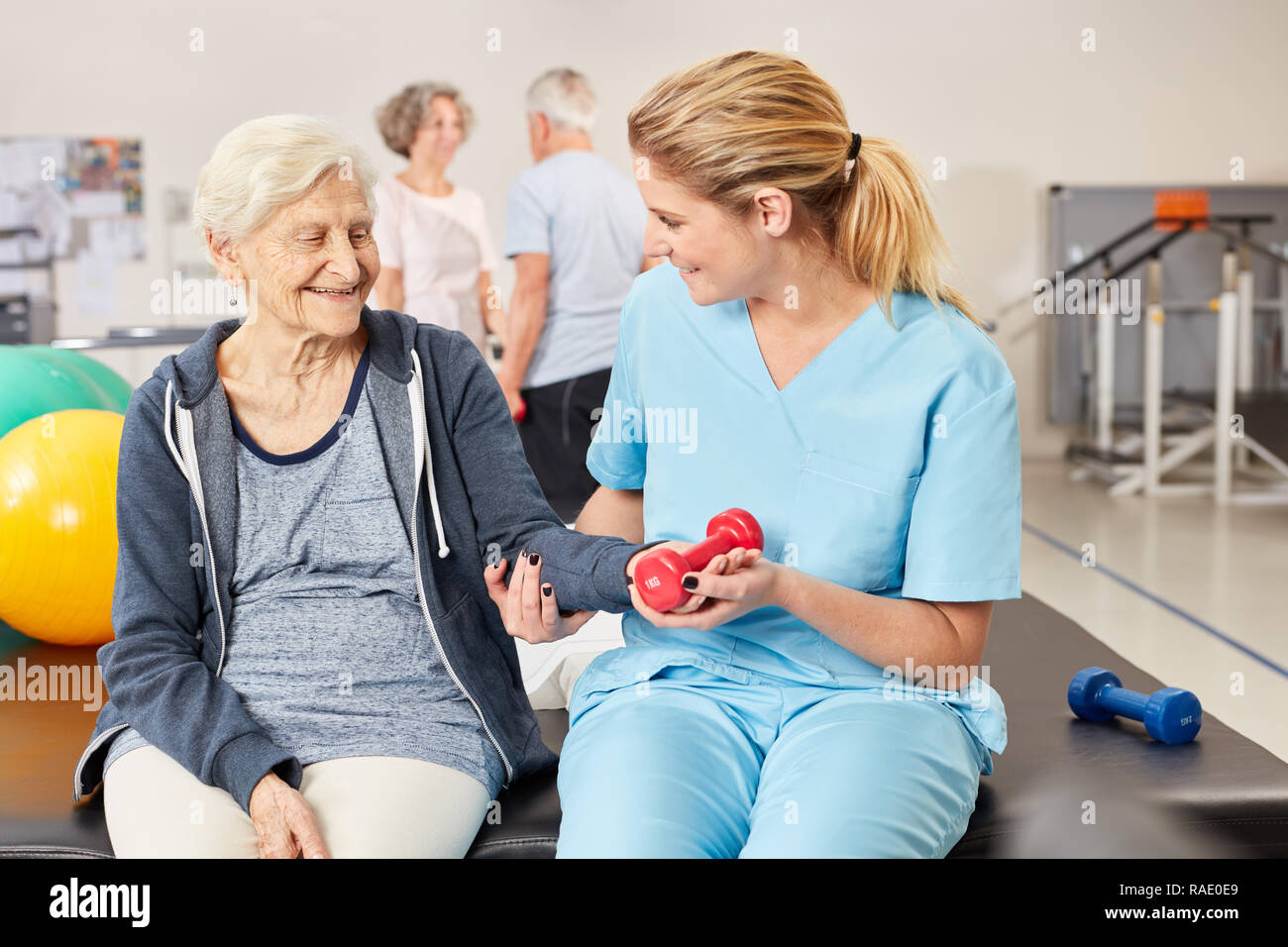 Ältere Frau zu tun Hantel Training in der Physiotherapie mit Therapeuten Stockfoto