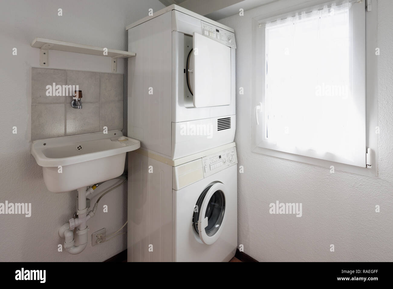 Waschküche mit Waschmaschine und Trockner übereinander gestapelt. Stockfoto