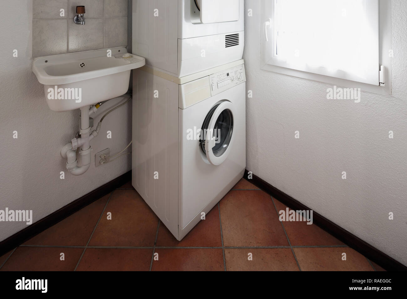 Waschküche mit Waschmaschine und Trockner übereinander gestapelt. Stockfoto