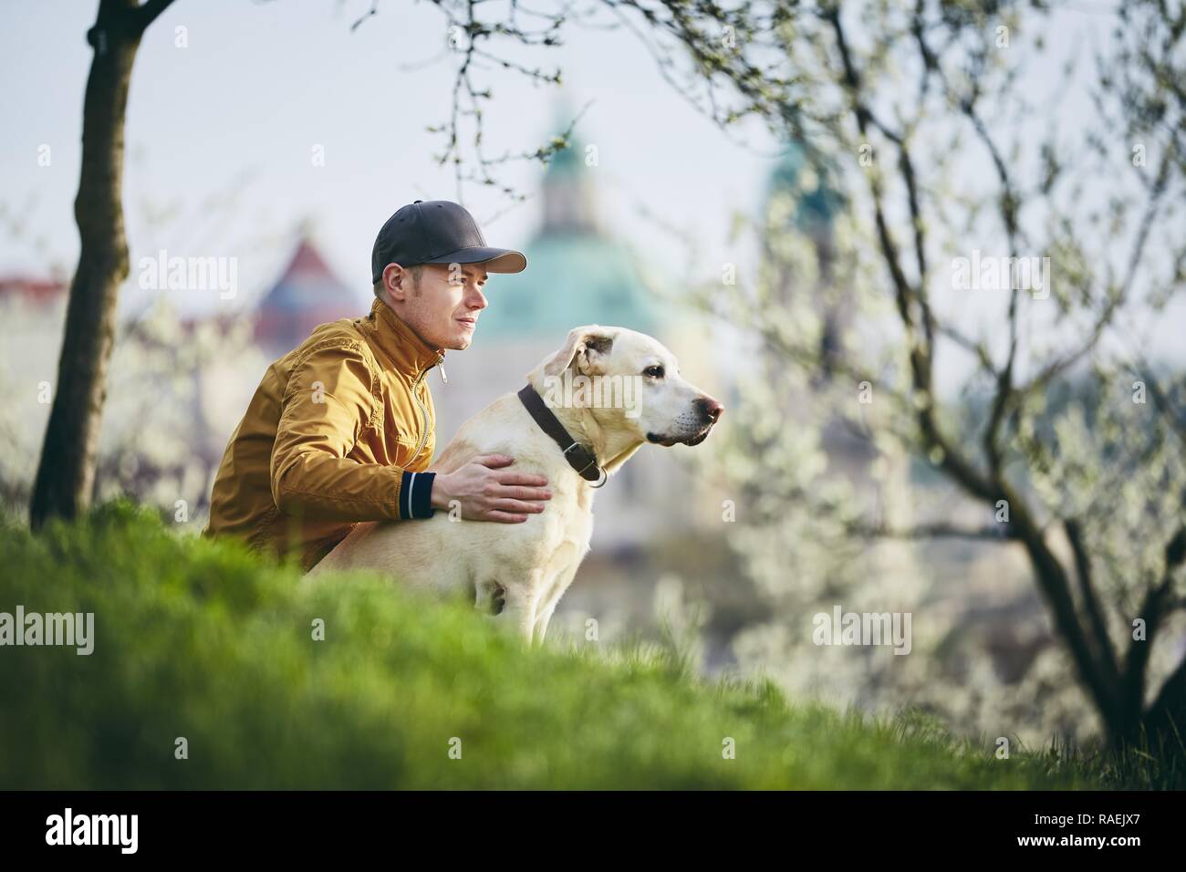 Junger Mann mit seinem Hund. Tierhalter Entspannung mit Labrador Retriever auf Gras im öffentlichen Park. Prag, Tschechische Republik. Stockfoto