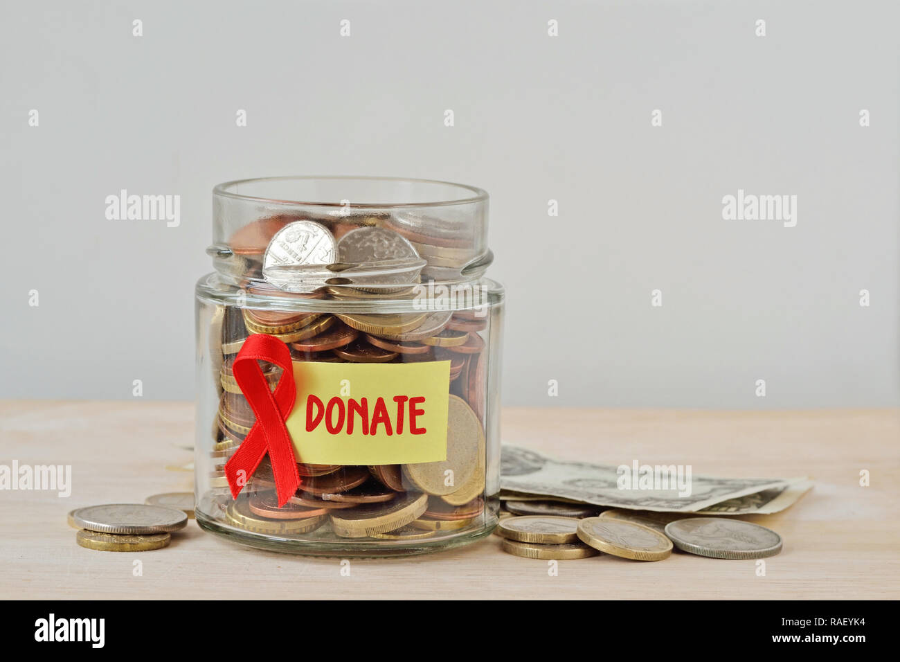 Geld Glas voll von Münzen mit rotem Band und Label Spenden - die AIDS-Hilfe und Forschung Fonds Konzept Stockfoto
