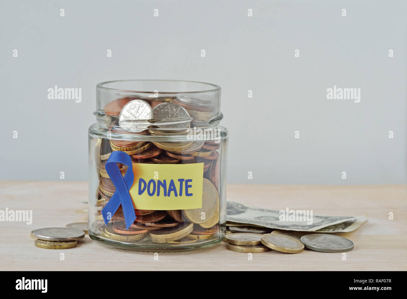 Geld Glas voll von Münzen mit blauen Band und Label Spenden - Begriff des Prostatakrebses Nächstenliebe und Forschungsfonds Stockfoto