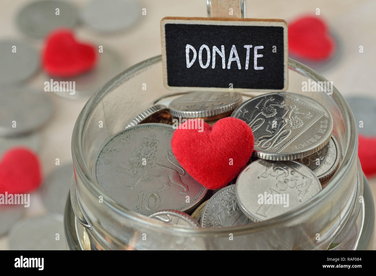 Münzen und Herzen aus Glas Glas mit Label Geld spenden - Nächstenliebe Konzept Stockfoto