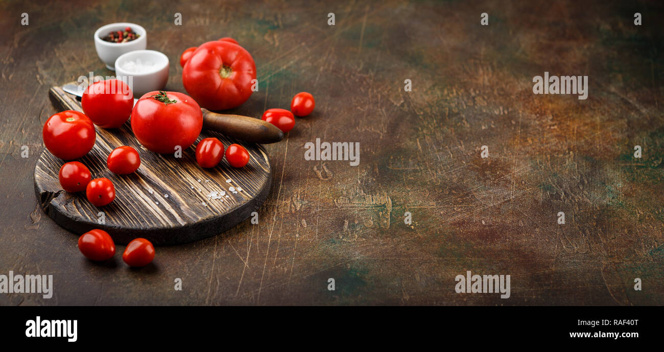 Frische Tomaten, alte Messer, Salz und Pfeffer auf Holzbrett. Platz für Text. Lange breite Banner Stockfoto