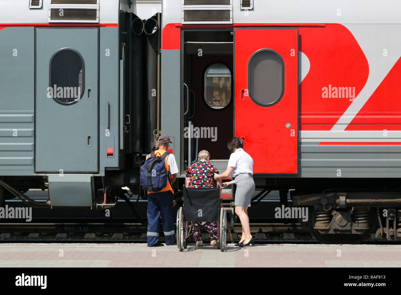 Mitarbeiter der Bahnhof Hilfe Eine behinderte Frau mit einer behinderten Person in einem Zug Auto zu erhalten. Stockfoto