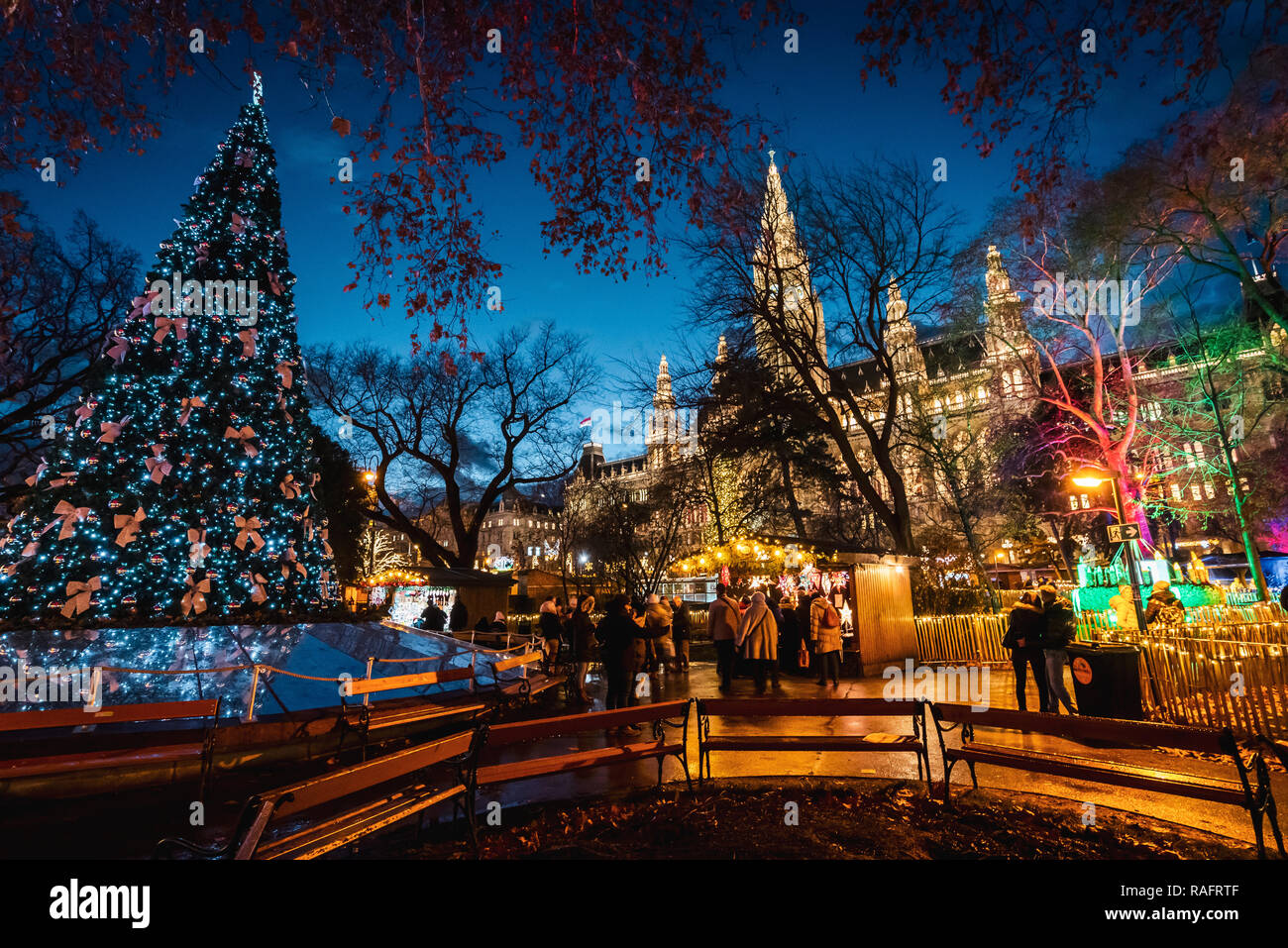 Night Shot der Weihnachtsmärkte am Rathausplatz, beleuchtete verzierten Baum mit bunten Lichtern, Rathaus im Hintergrund Stockfoto