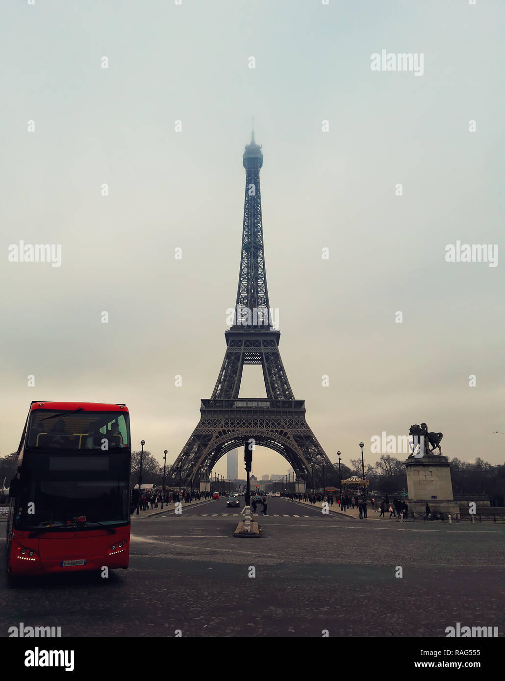 Ein roter Bus auf dem Bürgersteig und Straße vor der berühmten Pariser Sehenswürdigkeiten Blick auf den Eiffelturm von der Straße. Stockfoto