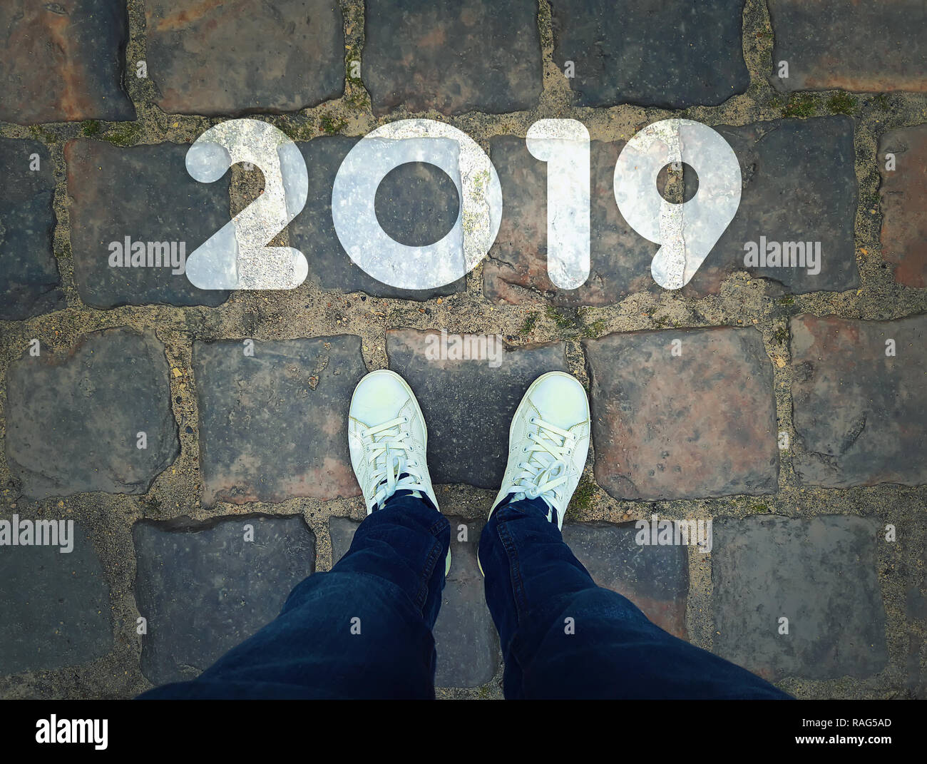 Blick von oben auf ein Mann, in weißen Turnschuhen auf vintage Bürgersteig Hintergrund Neben 2019. Starten eines neuen Jahres Herausforderung Konzept. Stockfoto