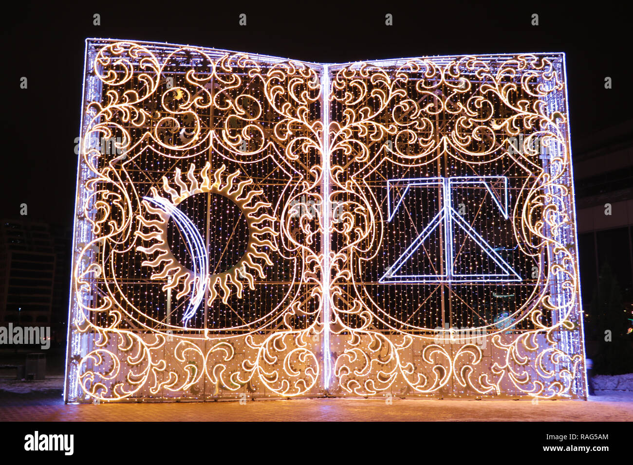 Minsk, Weißrussland - Dezember 25, 2018: Installation von dekorativen Buch mit Licht in der Nähe der Nationalen Bibliothek von Weißrussland. Zeichen der Skorina Stockfoto