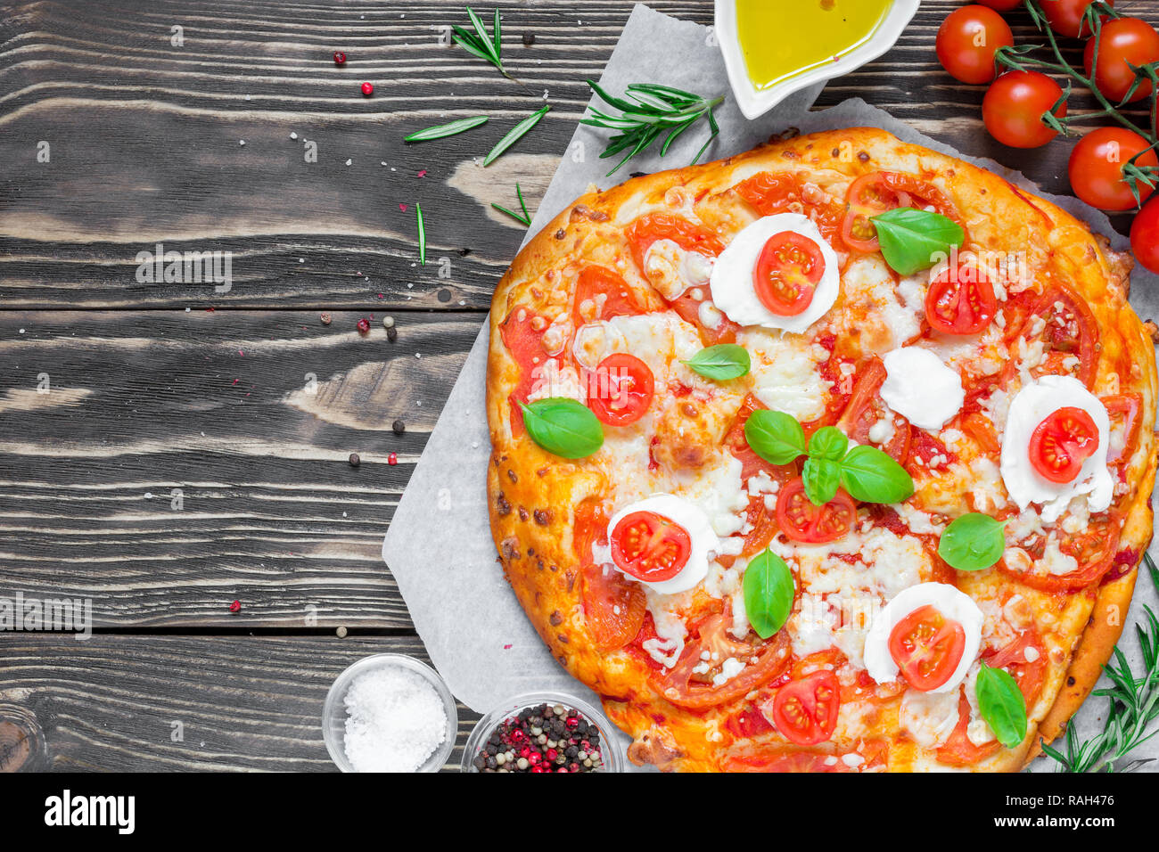 Hausgemachte Pizza Margherita mit Tomaten, Basilikum, Rosmarin und Mozzarella über rustikal Hintergrund. Ansicht von oben mit der Kopie Raum Stockfoto