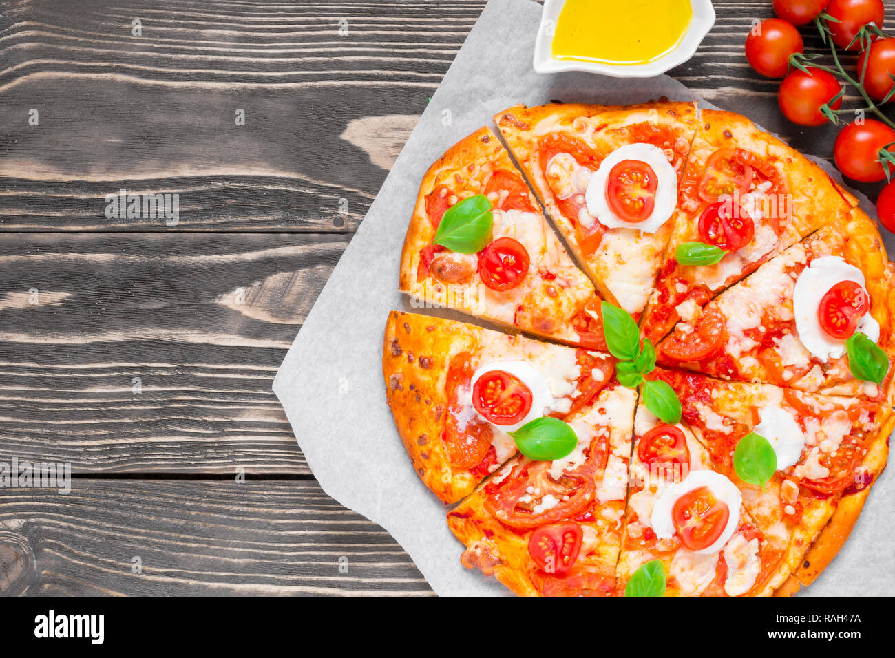 In Scheiben geschnittene hausgemachte Pizza Margherita mit Tomaten, Basilikum, Rosmarin und Mozzarella über rustikal Hintergrund. Ansicht von oben mit der Kopie Raum Stockfoto