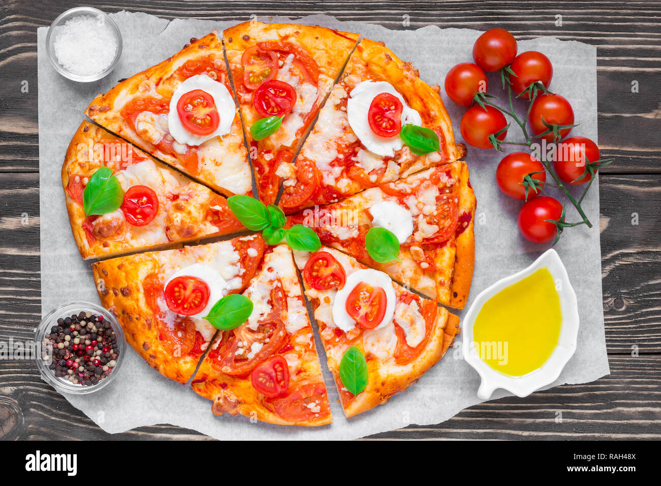 In Scheiben geschnittene hausgemachte Pizza Margherita mit Tomaten, Basilikum, Rosmarin und Mozzarella über rustikal Hintergrund. top View Stockfoto