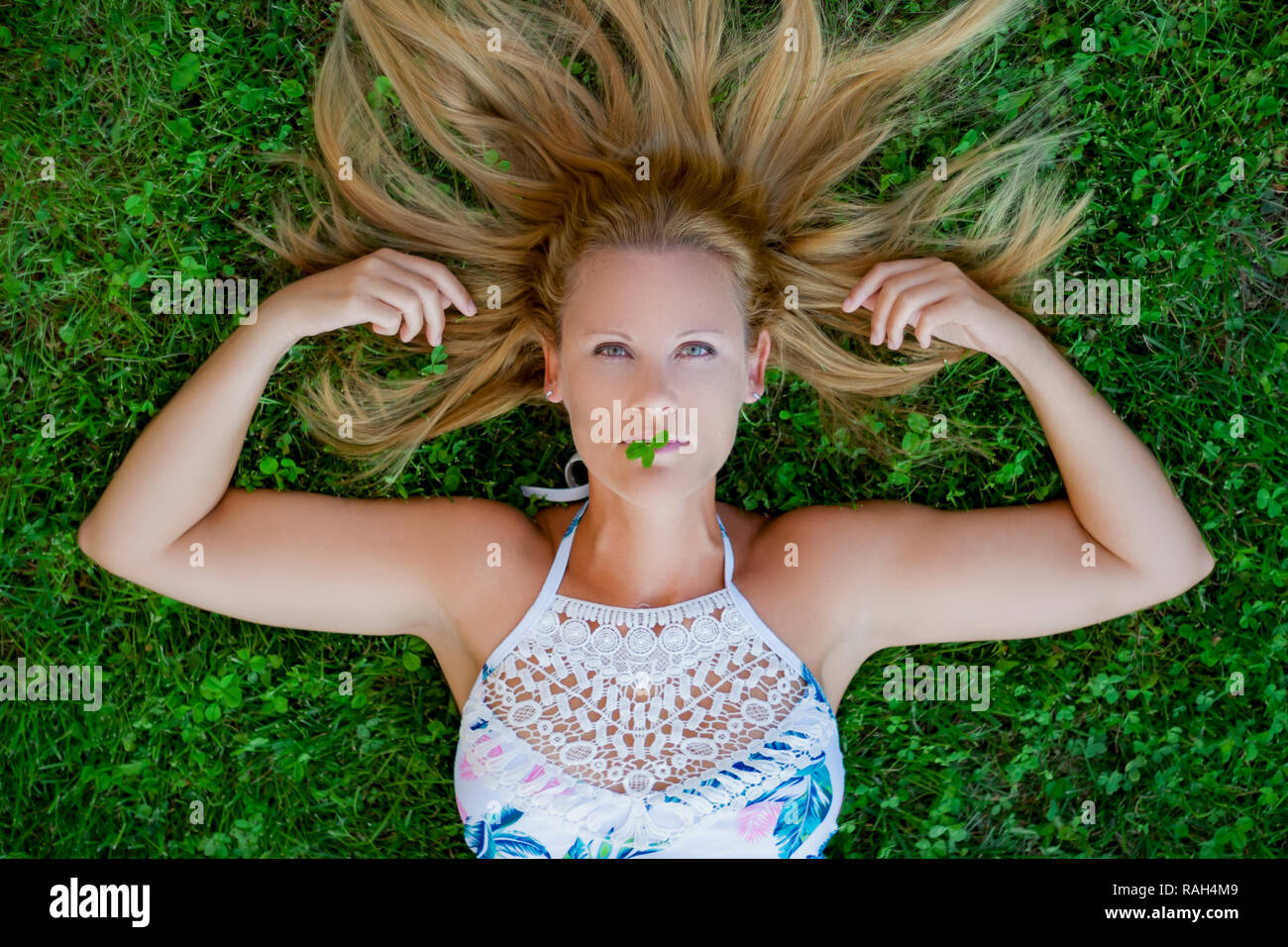 Portrait von blonde Frau in die Kamera schaut. Liegend auf dem Gras. Grüne Augen. Madrid, Spanien. Stockfoto
