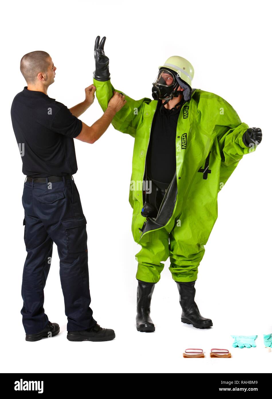 Feuerwehrmann helfen ein Kollege auf ein Chemikalienschutzanzug mit Luft aus einem Druckluft Atemschutzgeräte, Stockfoto