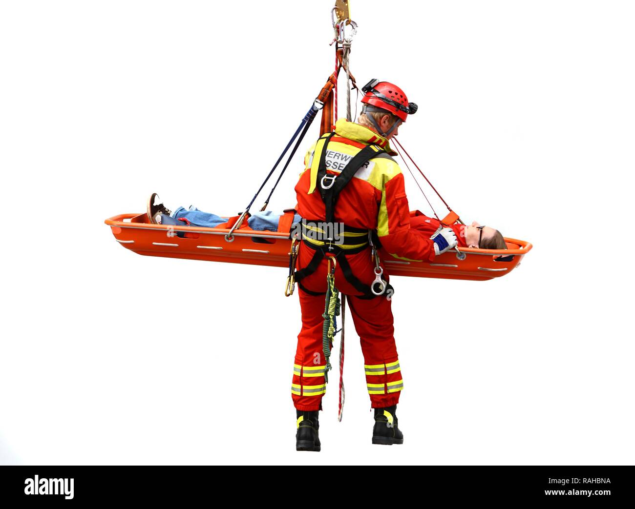 Hoher winkel Retter abseilen, während die Rettung einer Person in einer Rettung Korb, einem professionellen Feuerwehrmann der Berufsfeuerwehr Stockfoto