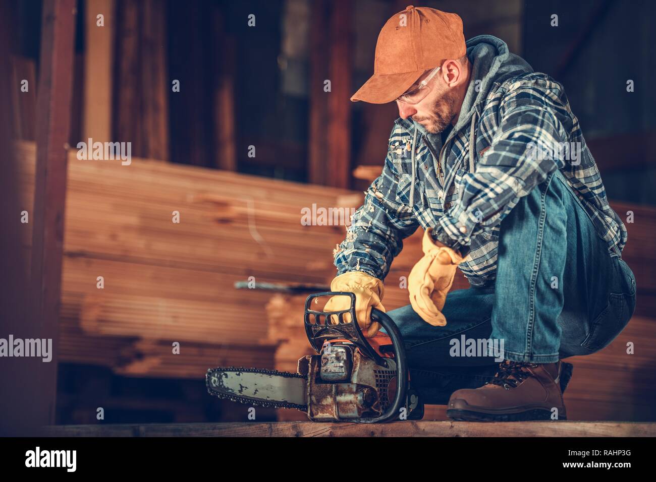 Kaukasische Auftragnehmer in seinem 30s mit einer Kettensäge. Vorbereitung der Ausrüstung für den Job. Stockfoto
