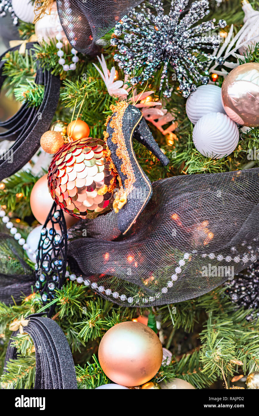 Lady's high-heeled Shoe hängt an einem Weihnachtsbaum mit Spielzeug und Girlanden, Kugeln und Schneeflocken, Perlen und leuchtende Lampen dekoriert Stockfoto