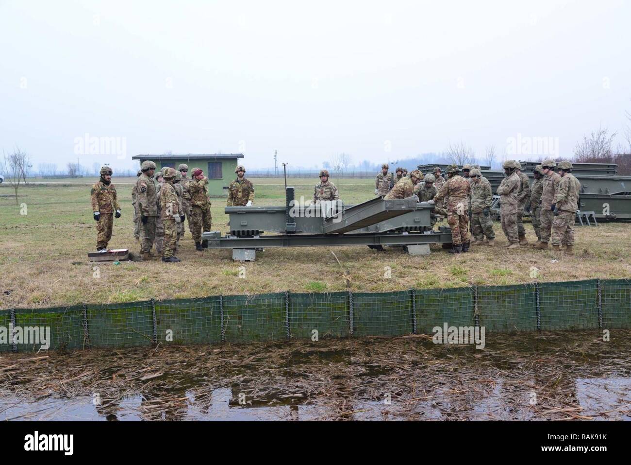 Us-Armee Fallschirmjäger auf die 173Rd Airborne Brigade Brigade, die 54Th Engineer Battalion und italienischen Soldaten aus dem 8 Reggimento Genio Guastatori Brigata Paracadutisti Folgore zugeordnet ein Medium Girder Bridge in der Nähe von Rovigo, Italien, 13.02.2017, zusammenbauen. Die MGB ist ein Deck, zwei girder Bridge, sie liefert einen 4 m (13 ft 2 in.) breite Fahrbahn, zügig mit minimaler Unterstützung zusammengebaut werden kann. Die 173Rd Airborne Brigade, in Vicenza, Italien, ist die US-Armee Contingency Response Force in Europa, die in der Lage ist, die Kräfte projizieren, das volle Spektrum militärischer Operationen zu acro Verhalten Stockfoto