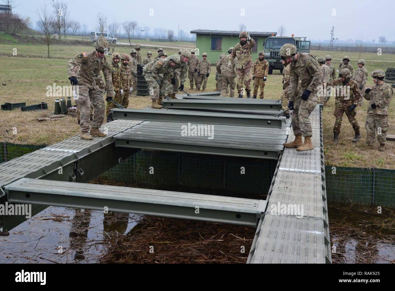 Us-Armee Fallschirmjäger auf die 173Rd Airborne Brigade Brigade, die 54Th Engineer Battalion und italienischen Soldaten aus dem 8 Reggimento Genio Guastatori Brigata Paracadutisti Folgore zugeordnet ein Medium Girder Bridge in der Nähe von Rovigo, Italien, 13.02.2017, zusammenbauen. Die MGB ist ein Deck, zwei girder Bridge, sie liefert einen 4 m (13 ft 2 in.) breite Fahrbahn, zügig mit minimaler Unterstützung zusammengebaut werden kann. Die 173Rd Airborne Brigade, in Vicenza, Italien, ist die US-Armee Contingency Response Force in Europa, die in der Lage ist, die Kräfte projizieren, das volle Spektrum militärischer Operationen zu acro Verhalten Stockfoto