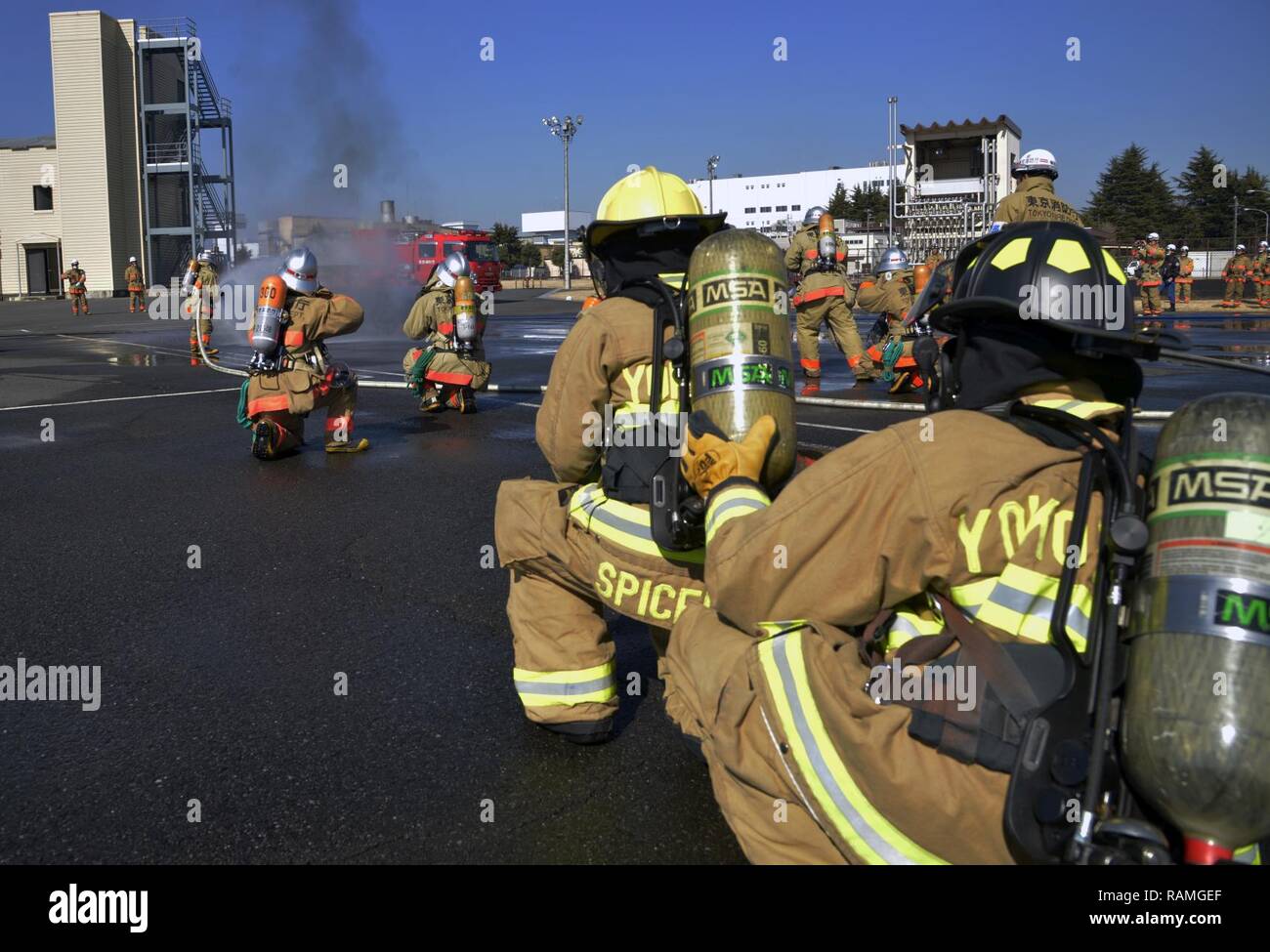 Die Feuerwehrleute aus der 374 Bauingenieur Squadron Feuerwehr zusehen, wie die Feuerwehrleute aus der Fussa Feuerwehr ein Fahrzeug Feuer bei einem Brand Ausbildung Szenario Yokota Air Base, Japan, Jan. 16, 2017. Jede Abteilung ging durch ihre eigene Taktik und Verfahren, die ein Fahrzeug Feuer zu löschen. Stockfoto