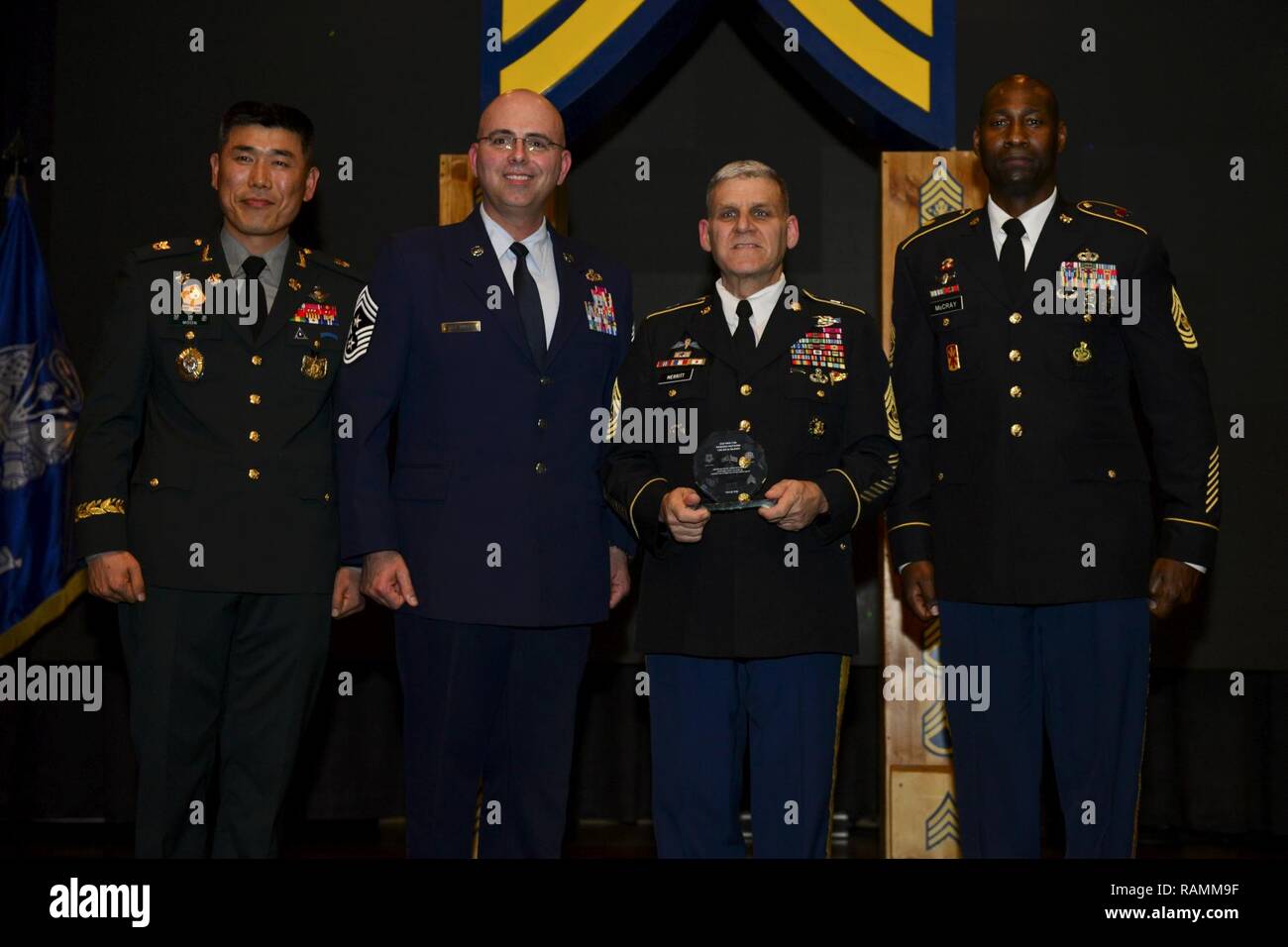 Command Sgt. Maj. Rick Merritt, achte Armee Command Sgt. Maj., erhält ein Zeichen der Wertschätzung von Command Sgt. Maj. Eric McCray, 35. ADA Brigade, rechts, Chief Master Sgt. Alexander Del Valle, 51th Fighter Wing, Links, und ROK Sgt. Maj. Moon, Byung-Joon, 6-52 ADA Bataillon, ganz links, denn, wie der Gastredner während des gemeinsamen NCO Induktion Zeremonie serviert. Feb 16 am Osan Flughafen. Stockfoto