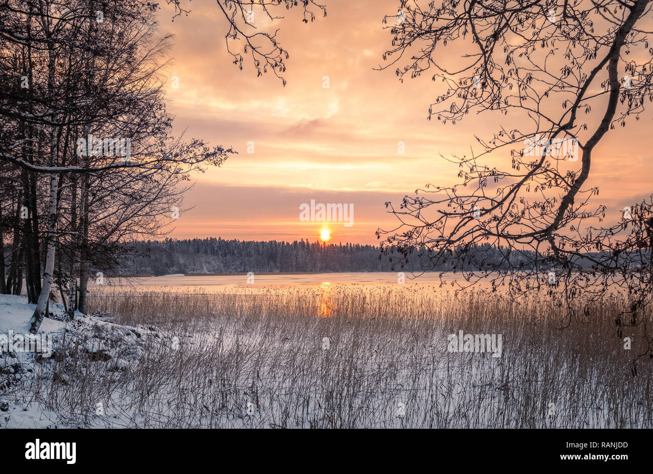 Malerische Winterlandschaft mit Sonnenuntergang am eisigen und friedlichen See in Finnland Stockfoto