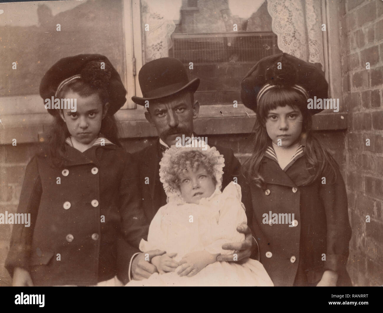 Vintage viktorianischen und edwardianischen Foto von einem Vater und seinen drei Töchtern. Das jüngste Kind Mai verstorbenen Aufgrund der Gesichtsausdruck. Stockfoto
