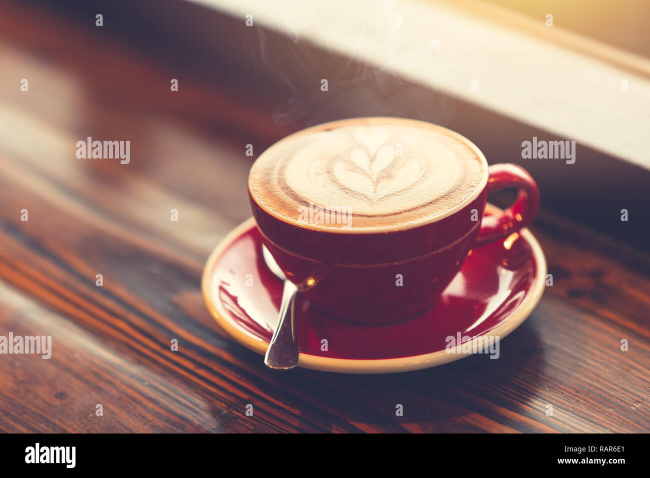 Guten Morgen Kaffee bei Windows auf Holztisch mit Latte Art vintage Farbton. Stockfoto