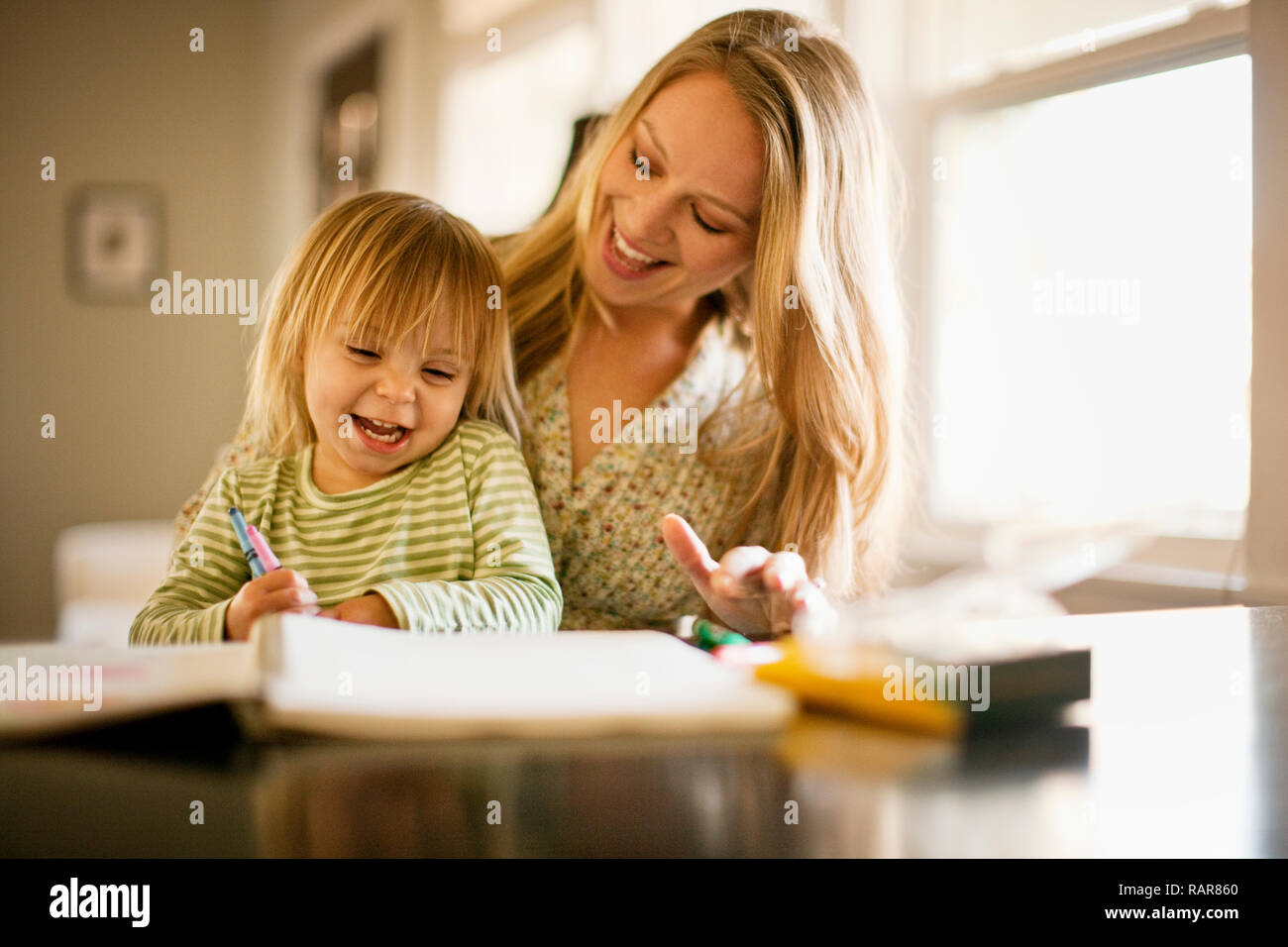 Junge Mädchen spielen mit einem Malbuch mit ihrer Mutter. Stockfoto